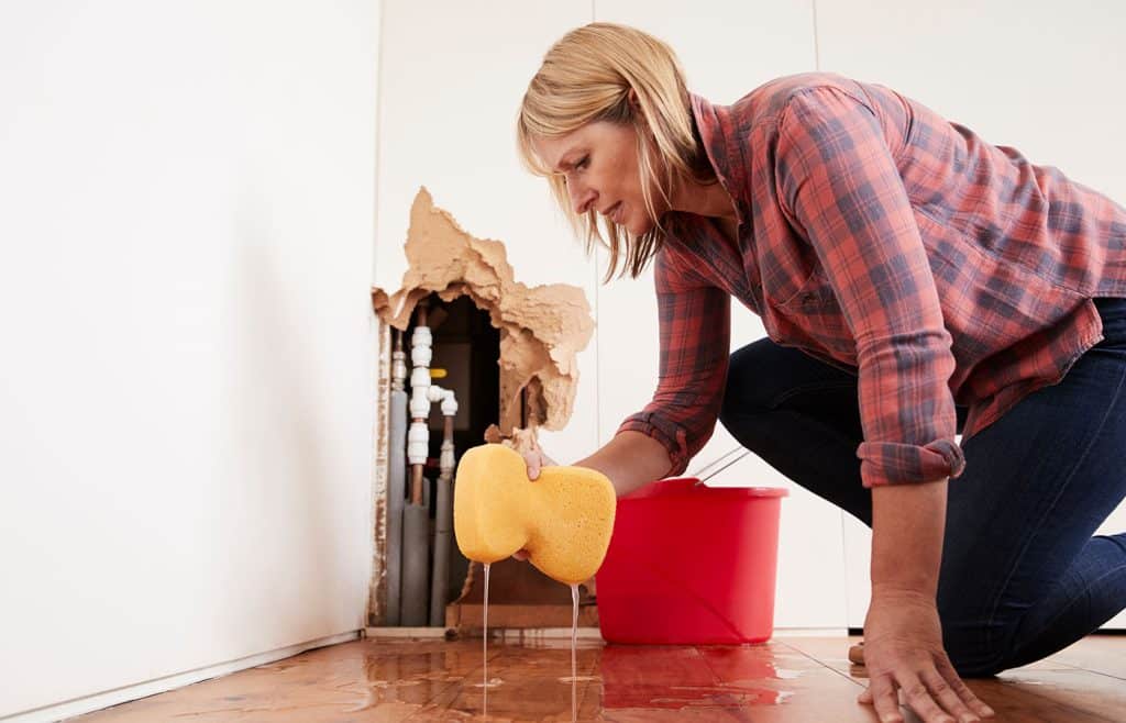 woman mopping up water from a burst pipe
